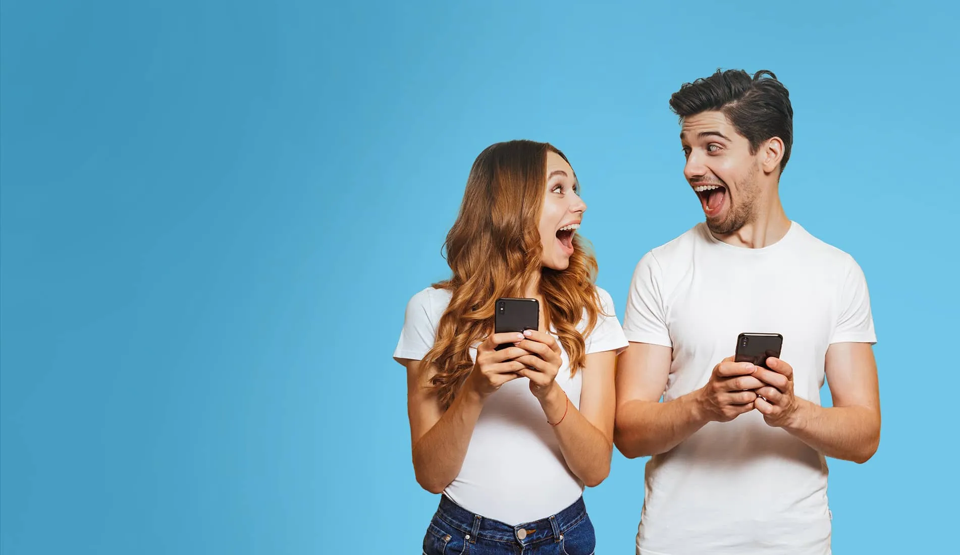 Ein Mann und eine Frau halten ihre Handys und lachen sich an