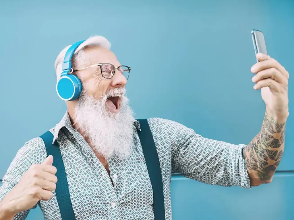 älterer Mann freut sich und guckt auf sein Handy