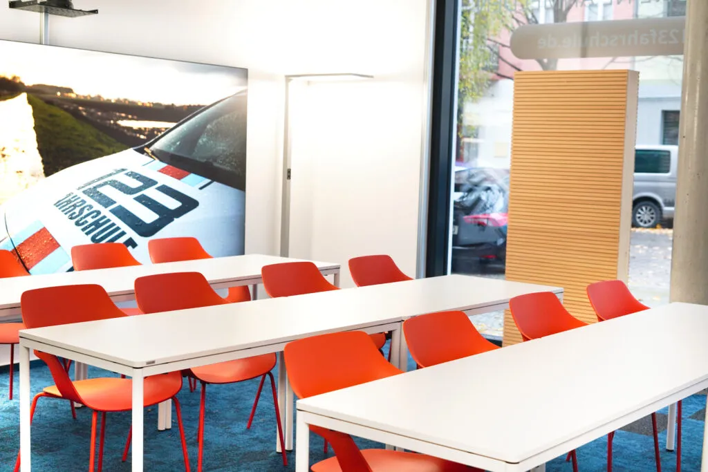 Theorieraum der 123Fahrschule mit weißen Tischen und orangenen Stühlen
