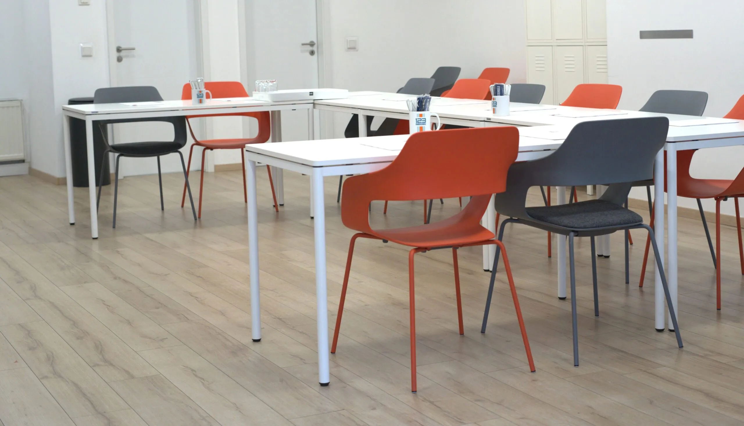 Filiale mit mehreren Tischen und Stühlen in orange, grau, weiß einer Fahrschule