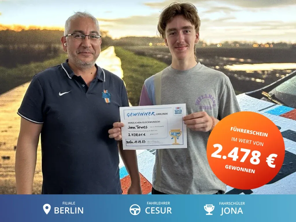 Fahrschüler steht rechts vom Fahrlehrer und hält eine Gewinnerurkunde im Wert von 2.478€ für die Führerscheinausbildung in der Hand