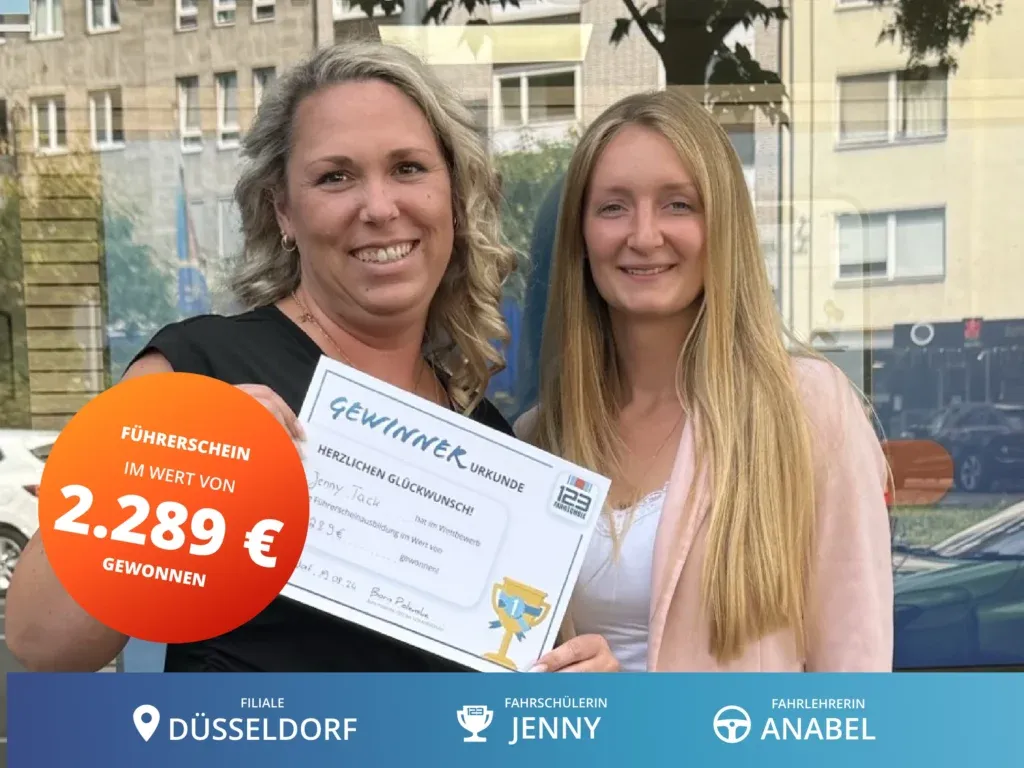 Fahrschülerin steht rechts neben Fahrlehrerin und hält eine Gewinnerurkunde im Wert von 2.289€ für die Führerscheinausbildung in der Hand