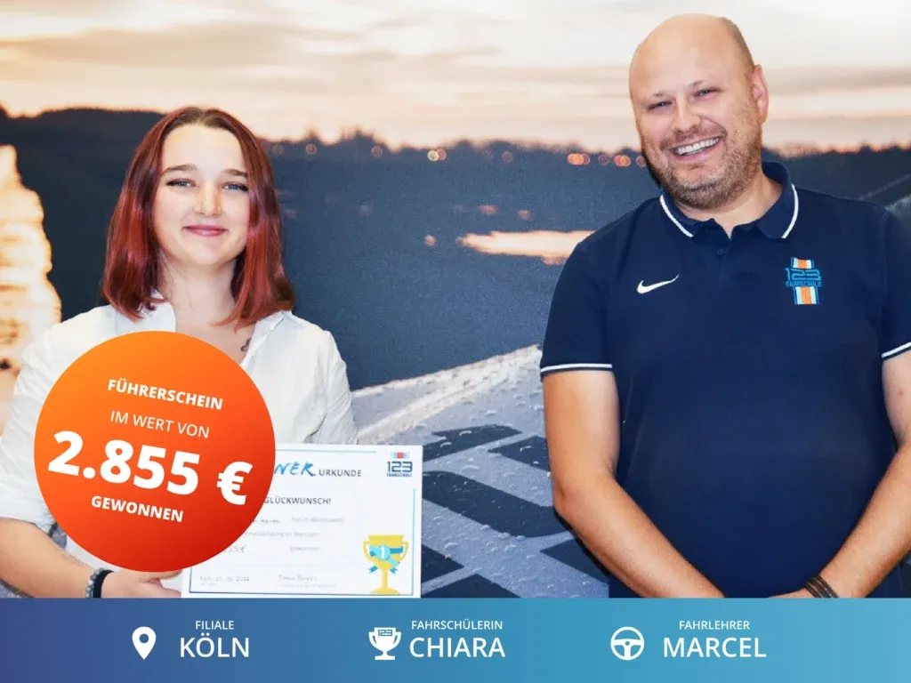 Fahrschülerin steht links vom Fahrlehrer und hält eine Gewinnerurkunde im Wert von 2.855€ für die Führerscheinausbildung in der Hand