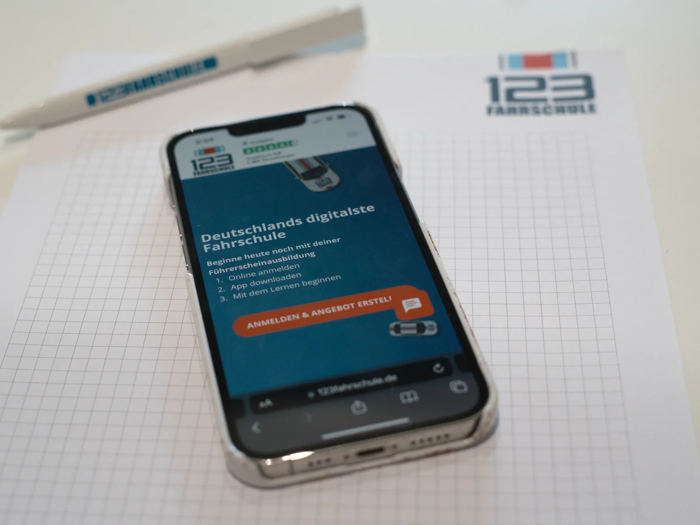 Ein iPhone auf dessen Screen die Website der 123fahrschule gezeigt wird.