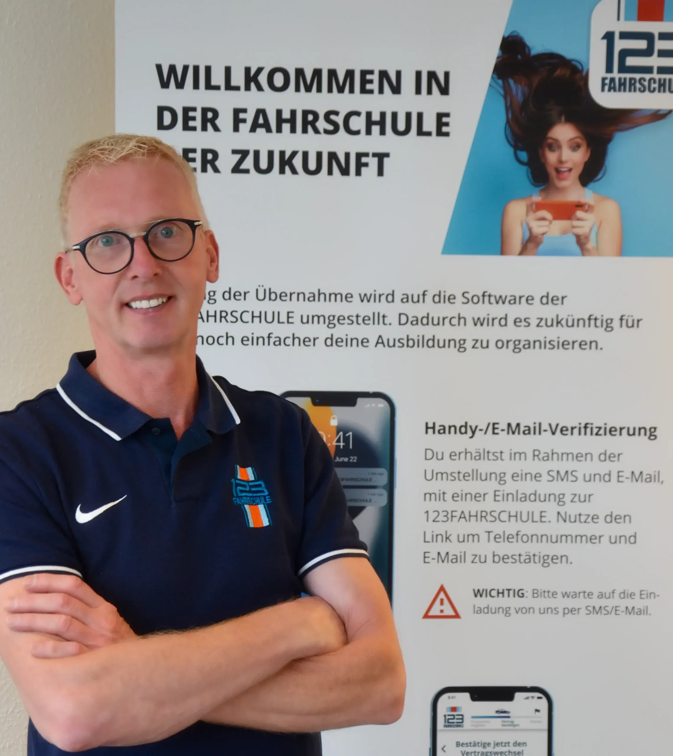 Fahrlehrer der 123 Fahrschule lehnt vor einem Werbe-Roll-Up