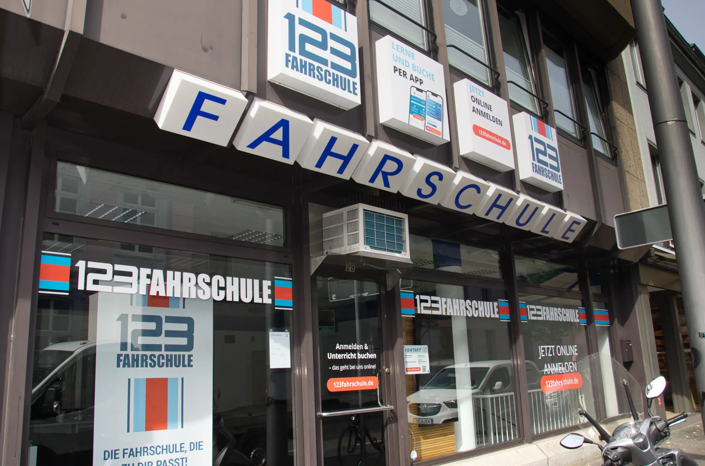 Filiale einer Fahrschule von außen mit Werbebotschaften am Schaufenster