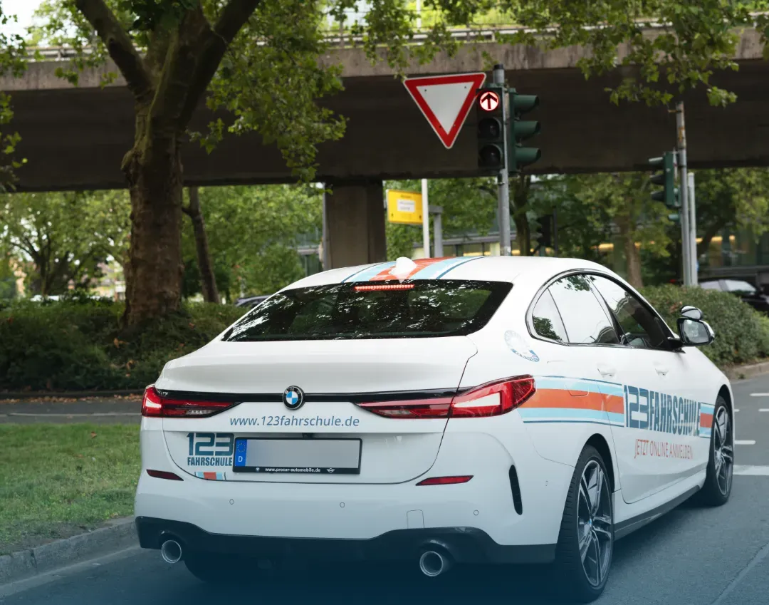 Ein Auto der 123 Fahrschule steht auf der Straße und hat Warnblinklicher an