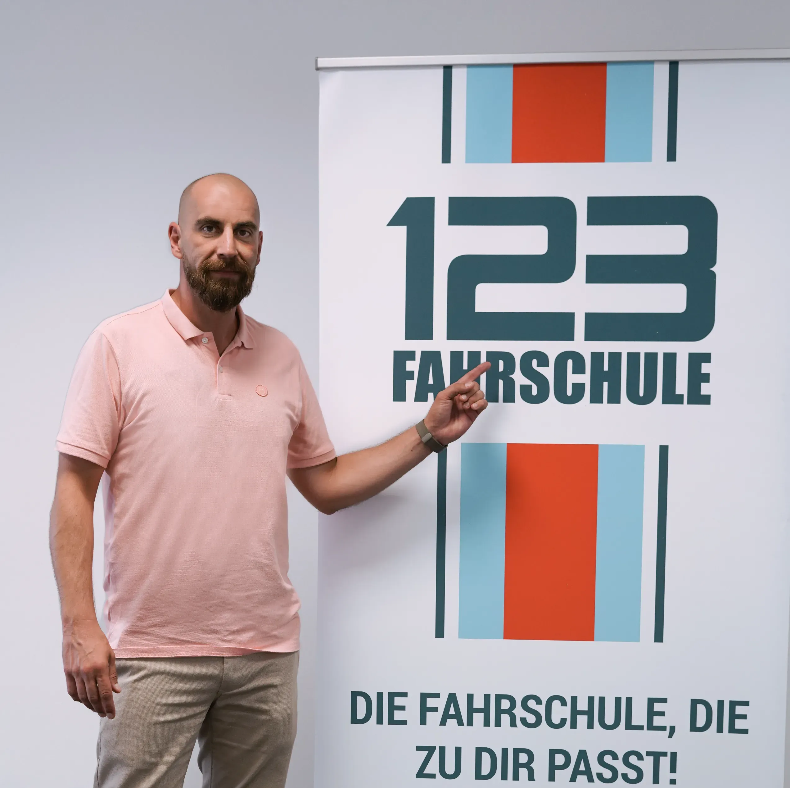 Fahrlehrer steht vor RollUp mit der Werbeaufschrift "123fahrschule"